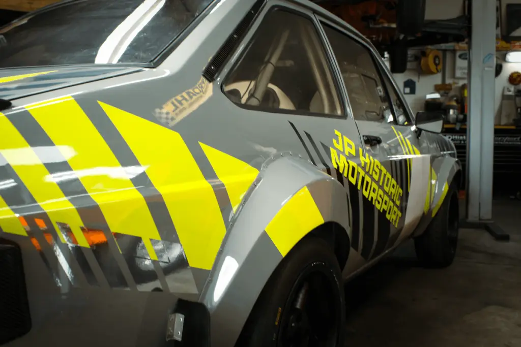 Photo of the back of the Ford Escort that we designed and wrapped. Fluo Yellow stripes on the back and some chrome stripes.